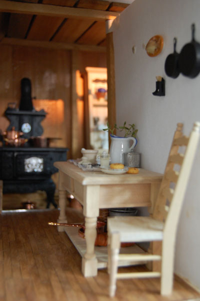 Photo of miniature work table with a cast iron stove in the background.